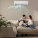 Happy family resting under air conditioner on beige wall at home